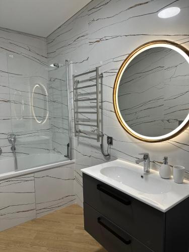 a bathroom with a sink and a mirror and a tub at Апартаменти Мон Блан in Khmelʼnytsʼkyy