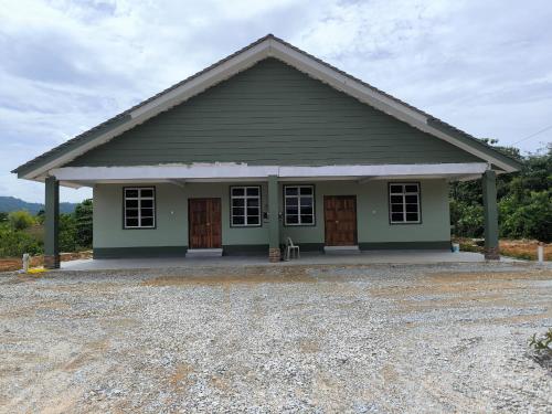 a green house with brown doors and a gravel driveway at Natures Haven Homestay II in Kampong Lubok Panjang