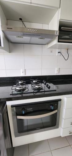 a white kitchen with a stove top oven at Condomínio Encantador (Blue das Americas) in Rio de Janeiro