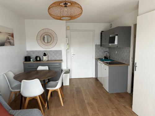 Una cocina y un comedor con mesa y sillas. en Cabourg Proche Thalasso, en Cabourg