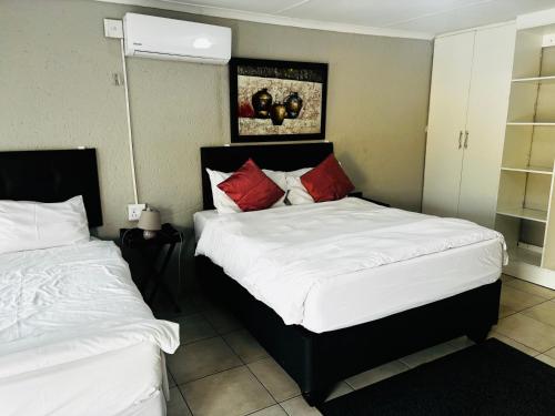a bedroom with two beds with white and red pillows at BTV Guesthouse in Hazyview