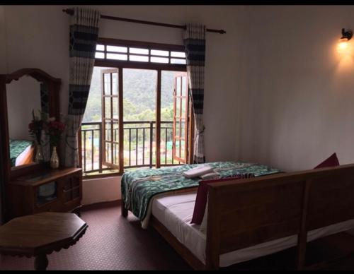 a bedroom with a bed and a large window at King's Lodge in Nuwara Eliya