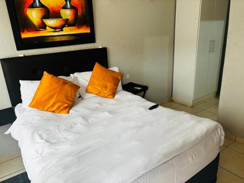 a white bed with two orange pillows on it at BTV Guesthouse in Hazyview