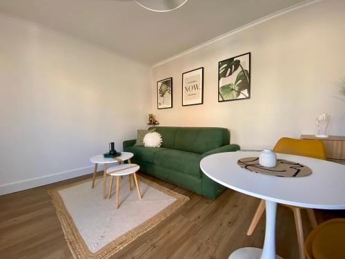 un salon avec un canapé vert et une table dans l'établissement Studio pour deux avec terrasse aux portes de la Camargue, à Aigues-Mortes