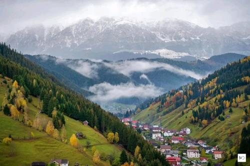 a town on a hill with mountains in the background at Pensiunea Hanul Dorului in Drumu Carului