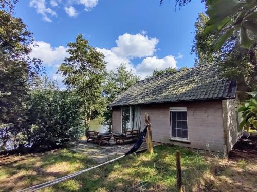 a small white building with a roof at Huisje aan het water in Lichtervelde