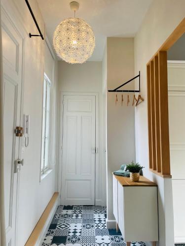 a hallway with a chandelier and a white door at Cosy chic, raffiné et spacieux en hyper centre in Arras