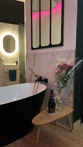 La salle de bains est pourvue d'une baignoire et d'une table avec une bouteille de bière. dans l'établissement L evazion appartement Grenoble, à Grenoble