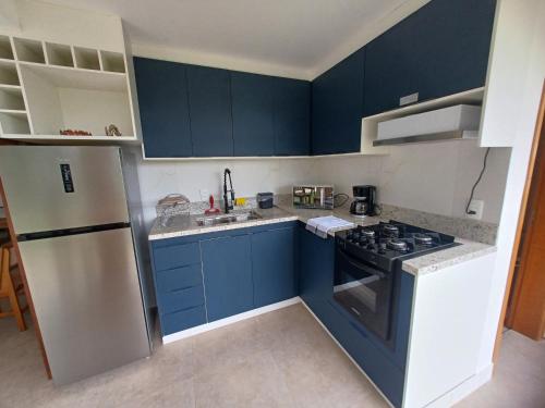 a kitchen with blue cabinets and a stove top oven at Linda Casa de hóspedes em condomínio in Itupeva