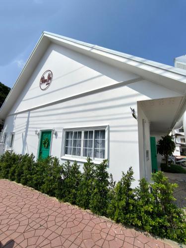 a white house with green doors and a driveway at Ban Ye in Phayao