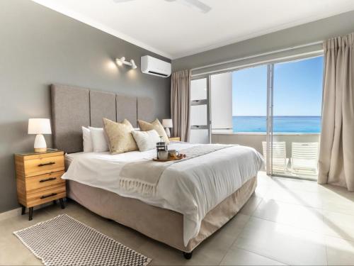 a bedroom with a bed with a view of the ocean at Beachfront Apartment Shakas Rock - Martinique, Pool, Ocean Views in Ballito