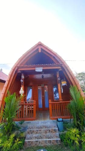 a wooden house with a large front porch at Green Pacing Lodge in Bangli