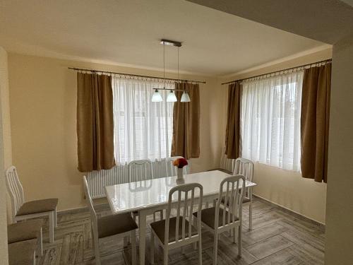 a dining room with a white table and chairs at Pensiunea Cris in Pădureni