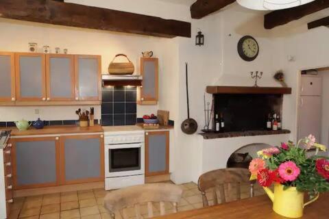 une cuisine avec une table et une horloge au mur dans l'établissement Le Portail Neuf, à Beaumes-de-Venise