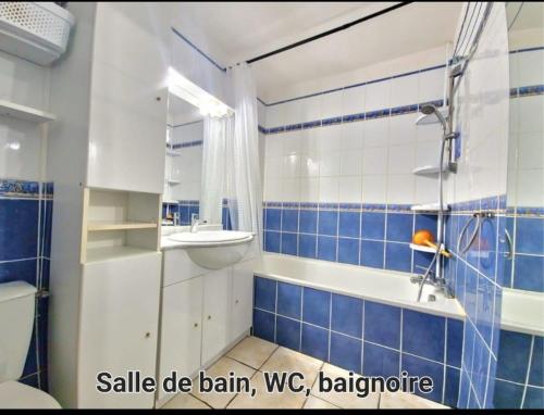 La salle de bains bleue et blanche est pourvue d'un lavabo et d'une baignoire. dans l'établissement 100m de la plage, jolie maison 5 personnes, CLIM, secteur Lydia Grande Plage, au Barcarès