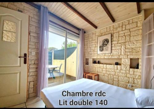 une chambre avec un lit et une porte coulissante en verre dans l'établissement 100m de la plage, jolie maison 5 personnes, CLIM, secteur Lydia Grande Plage, au Barcarès