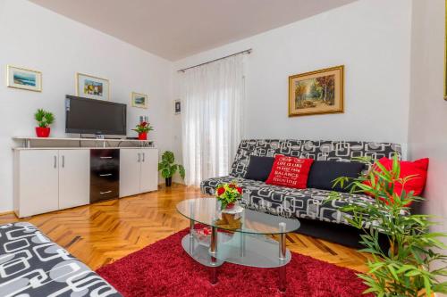 a living room with a couch and a tv at Apartments Kremenici in Malinska