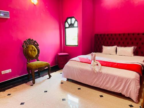 a pink bedroom with a bed and a chair at White palace airport transit Hotel in Katunayake