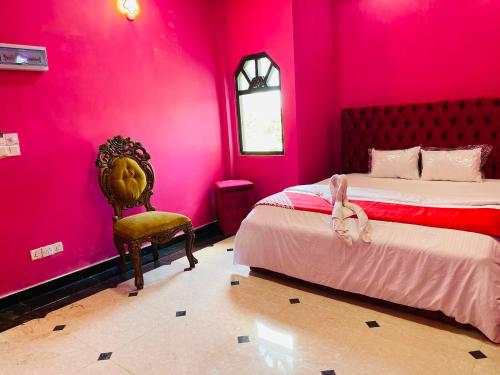 a bedroom with pink walls and a bed and a chair at White palace airport transit Hotel in Katunayake