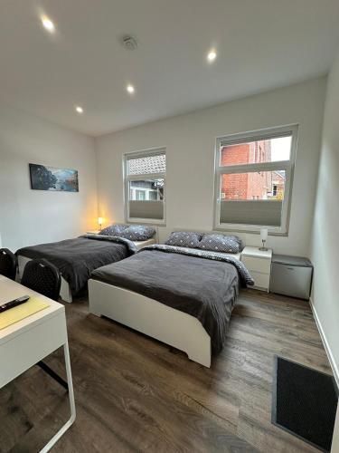 シュターデにあるGästehaus Bützfleth, Rad-Hotel, Arbeit & Privat, Bed & Breakfast, Mitten am Elb-Rad-Wanderwegのベッドルーム1室(ベッド2台、デスク、窓2つ付)
