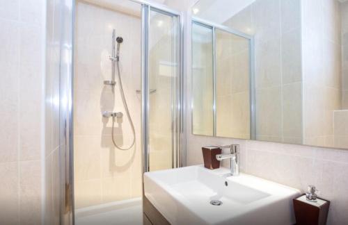 een witte badkamer met een wastafel en een douche bij La Grande Savoyarde in Chamonix-Mont-Blanc