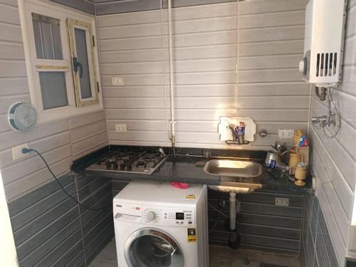 una pequeña cocina con lavadora y fregadero en luxury flat on blue meka beach, en Alejandría