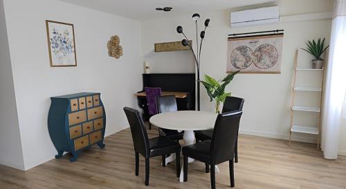 une salle à manger avec une table blanche et des chaises noires dans l'établissement Landon Cottage, à Campénéac