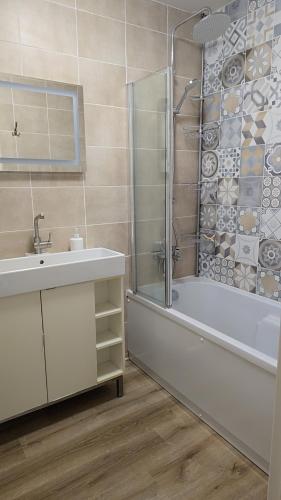 une salle de bain avec une baignoire, un lavabo et une douche dans l'établissement Landon Cottage, à Campénéac