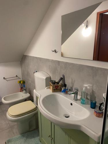 a bathroom with a sink and a toilet and a mirror at Monolocale Zefiro in Elmas