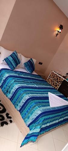 a bed with a striped blanket on top of it at Mirleft Tayought Guest House in Mirleft