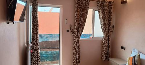 a room with two windows with curtains and a window at Mirleft Tayought Guest House in Mirleft