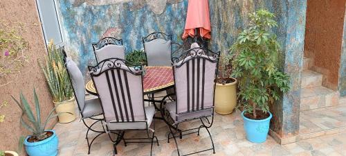 a patio with a table and chairs and potted plants at Mirleft Tayought Guest House in Mirleft