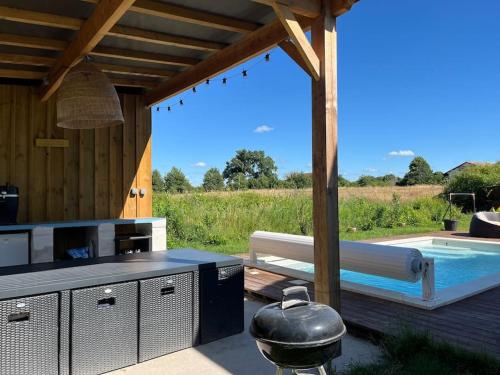 une cuisine extérieure avec un grill et une piscine dans l'établissement La maison du bonheur entre Bordeaux et Océan, à Saint-Médard-en-Jalles