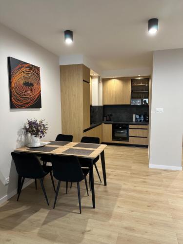a dining room with a table and chairs and a kitchen at Apartament M&A in Łomża