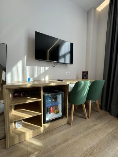 a desk with a television and two green chairs at Hotel Panorama & Spa Elbasan in Elbasan
