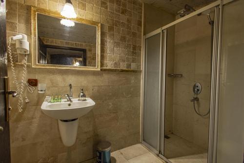 a bathroom with a sink and a shower with a mirror at Century Cave Hotel in Goreme