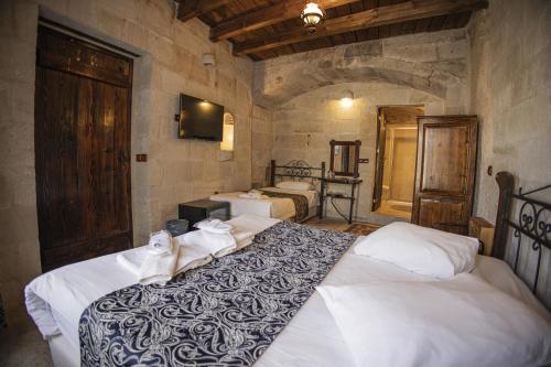 a bedroom with two beds in a stone room at Century Cave Hotel in Goreme