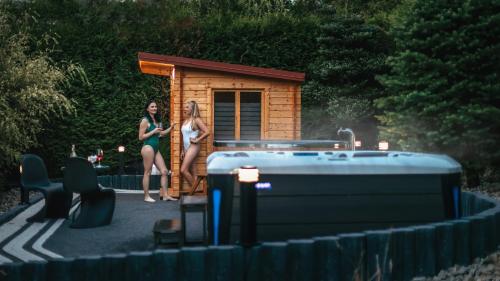 two women standing in front of a small cabin at APARTAMENTY VILLA PIGMALION - sauna, jacuzzi, parking, ogród in Kudowa-Zdrój
