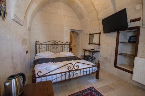 a bedroom with a bed with a tv on a wall at Century Cave Hotel in Goreme