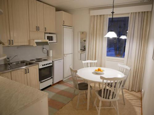 a kitchen with a white table and chairs and a table and a kitchen with at Riihipelto - A cozy house in the countryside in Rovaniemi