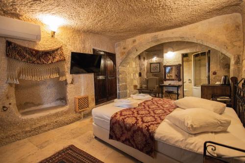 a bedroom with a large bed and a stone wall at Century Cave Hotel in Goreme