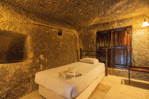 a bedroom with a bed in a stone wall at Century Cave Hotel in Goreme