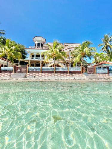 a building with palm trees in front of the water at Casaroyal Beachfront Siquijor in Siquijor