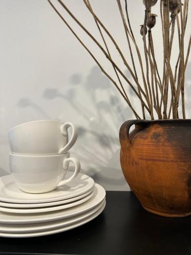 a coffee cup and plates on a table with a vase at Апартаменти Мон Блан in Khmelʼnytsʼkyy
