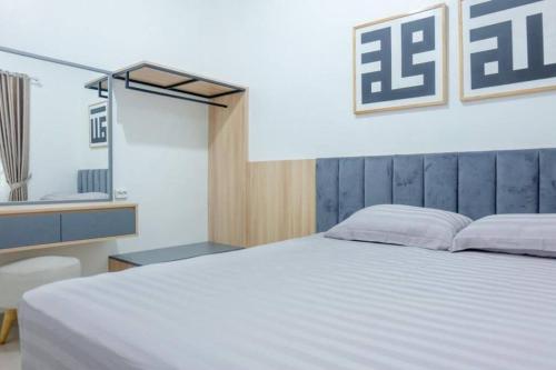 a bedroom with a large white bed and a mirror at Kamiliya Homestay in Ngabean