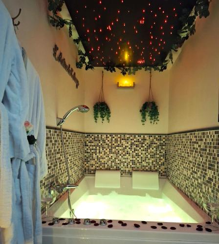 a bath tub in a bathroom with a tiled wall at L' Antre de L' Ange in Trédarzec