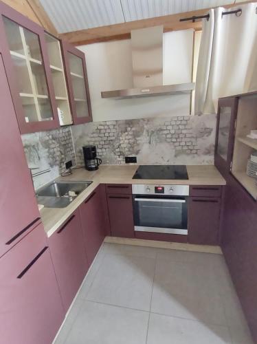 a kitchen with purple cabinets and a stove top oven at Huisje aan het water in Lichtervelde