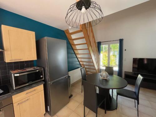 une cuisine et une salle à manger avec une table et un réfrigérateur dans l'établissement La Maison du Bonheur 2 ch 65m2 - patio et jardin - Les Mathes - Locsweethome, aux Mathes