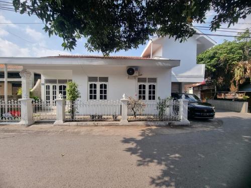a white house with a fence in front of it at Kamiliya Homestay in Ngabean