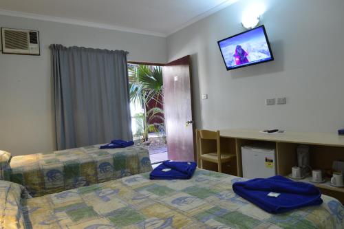 a hotel room with a bed and a tv on the wall at Goldfields Hotel Motel in Tennant Creek